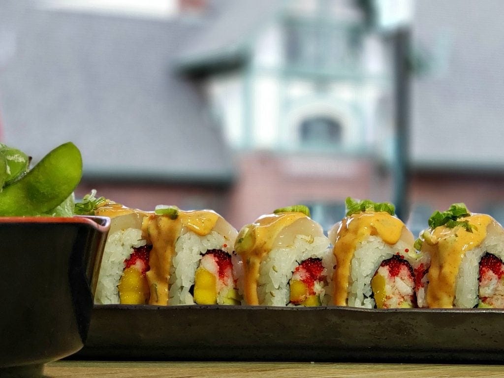 Sushi roll in long black black plate - Flagstaff historic depot can be seen through window