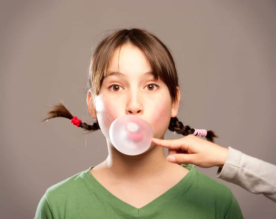 A young girl is chewing a bubblegum