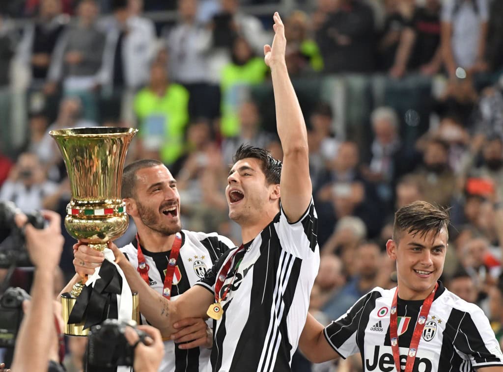 Juventus' defender from Italy Leonardo Bonucci (L), Juventus' forward from Spain Alvaro Morata (C) and Juventus' forward from Argentina Paulo Dybala celebrate with the trophy after winning the Italian Tim Cup final football match AC Milan vs Juventus on May 21, 2016 at the Olympic Stadium in Rome. Juventus won 0-1 in the extra time. AFP PHOTO / TIZIANA FABI / AFP / TIZIANA FABI (Photo credit should read TIZIANA FABI/AFP/Getty Images)