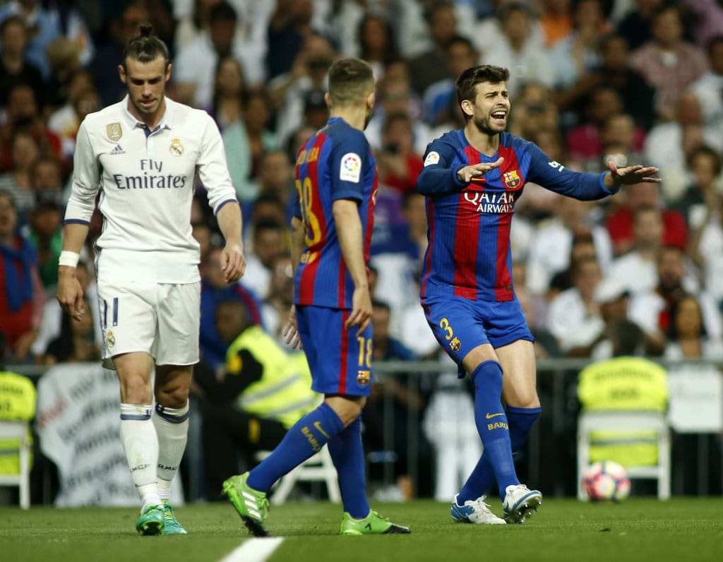 Barcelona's defender Gerard Pique (R) gestures beside Real Madrid's Welsh forward Gareth Bale (L) during the Spanish league football match Real Madrid CF vs FC Barcelona at the Santiago Bernabeu stadium in Madrid on April 23, 2017. / AFP PHOTO / OSCAR DEL POZO (Photo credit should read OSCAR DEL POZO/AFP/Getty Images)