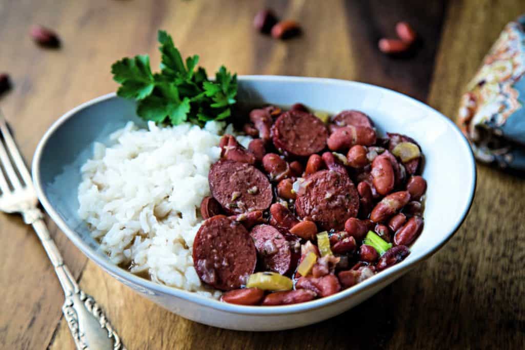 red beans and rice in a white bowl with a fork on a wooden table