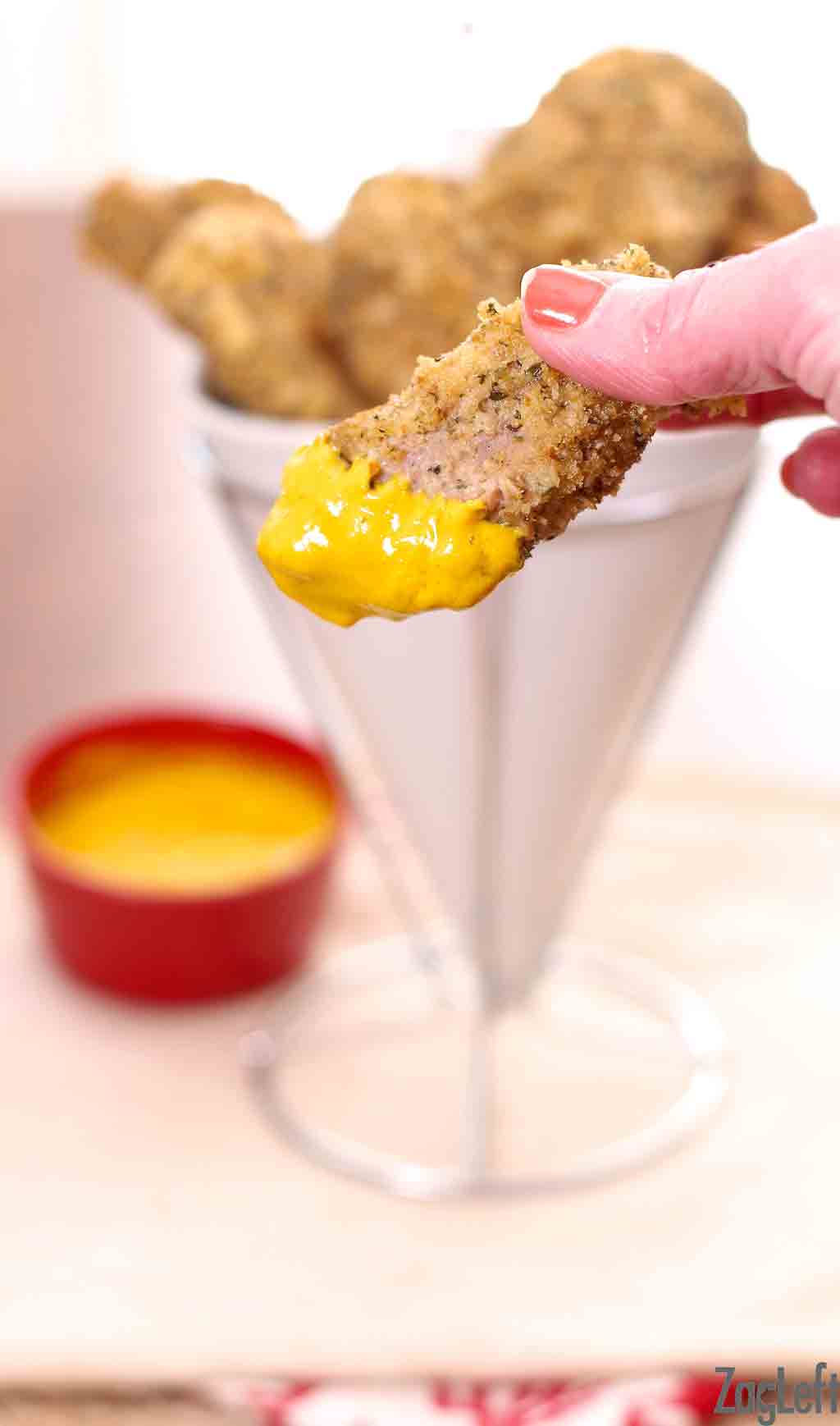 A chicken tender dipped in honey mustard