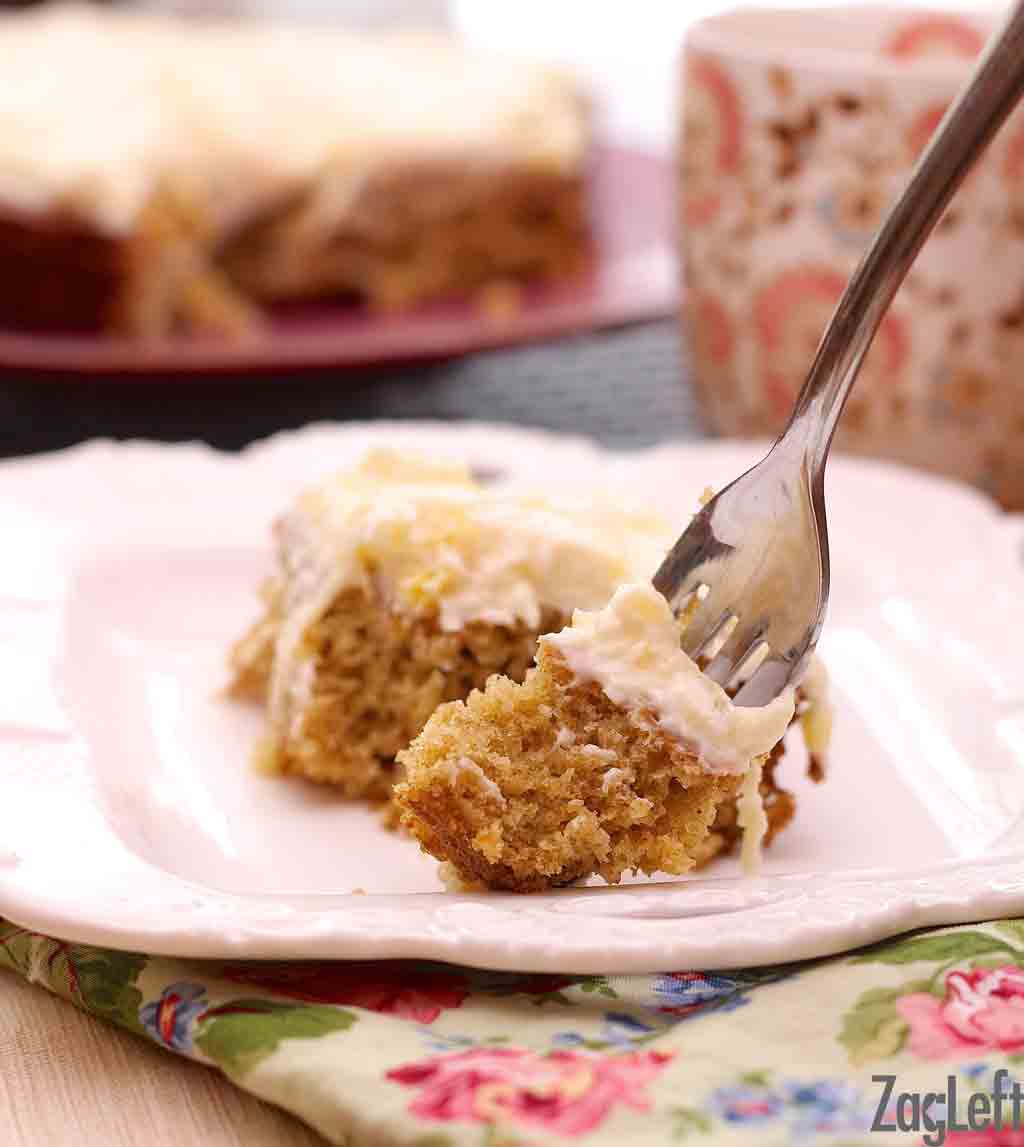 A closeup of a fork in a piece of pineapple oat cake plated on a floral cloth napkin