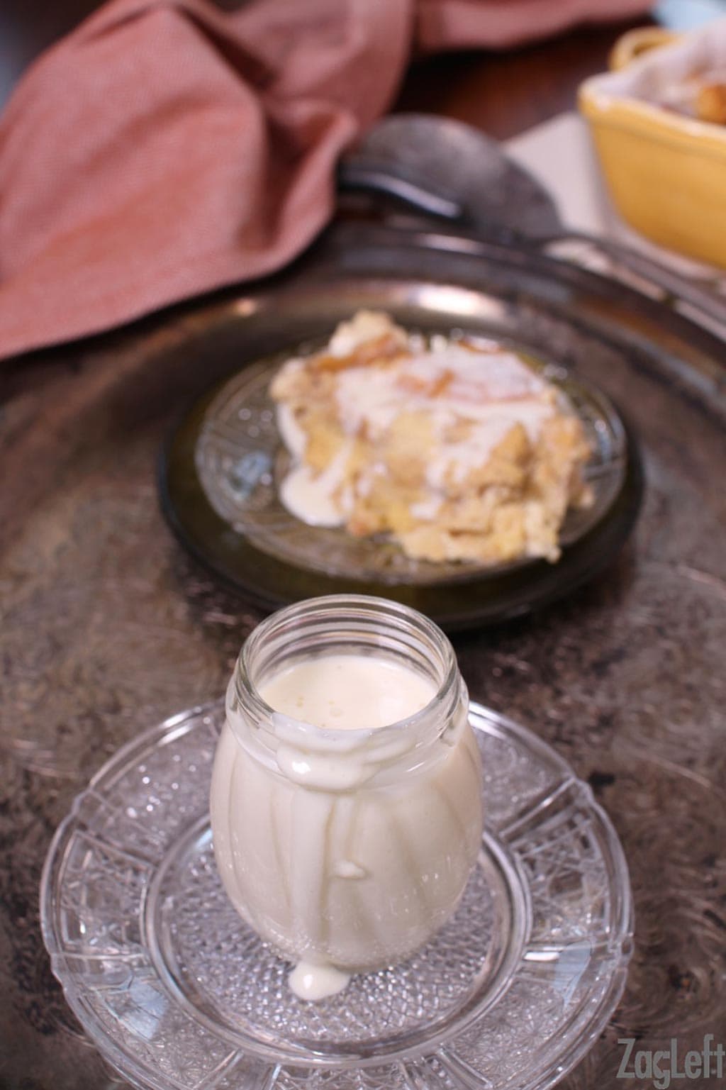 Whiskey sauce in a jar next to a plate of bread pudding