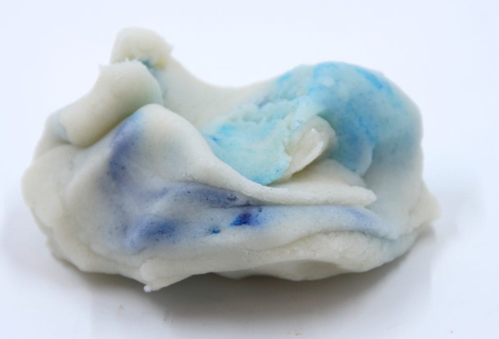 A photo of uncolored play dough that has blue streaks as students begin to play with it.