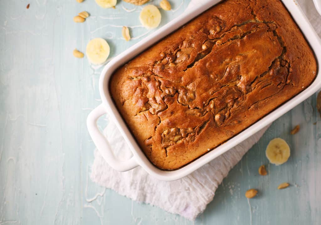 overhead view of a peanut butter banana bread cooling in a white loaf pan.