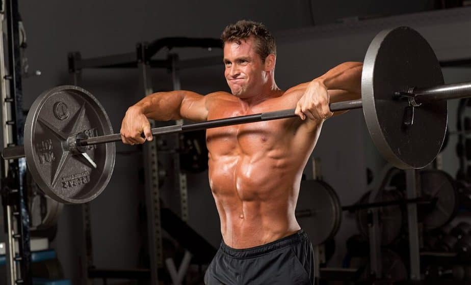 A guy has a training with the barbell at the gym