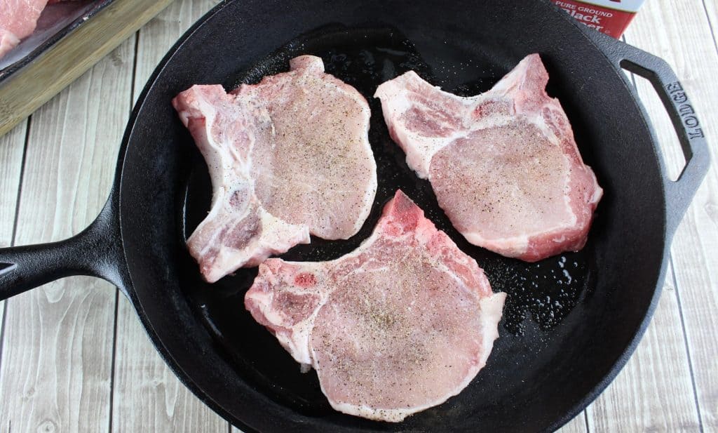 pork chops frying in lodge cast iron pan
