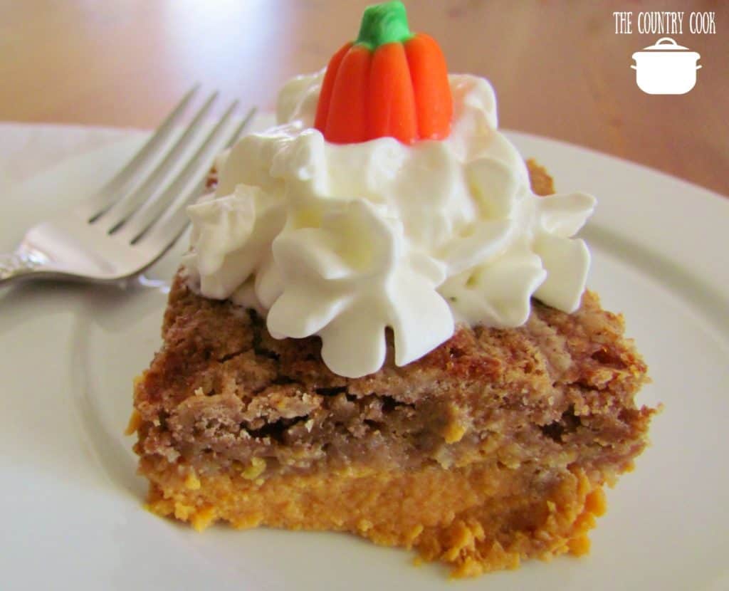 Pumpkin Pie Dump Cake slice toped with whipped cream and a candy pumpkin