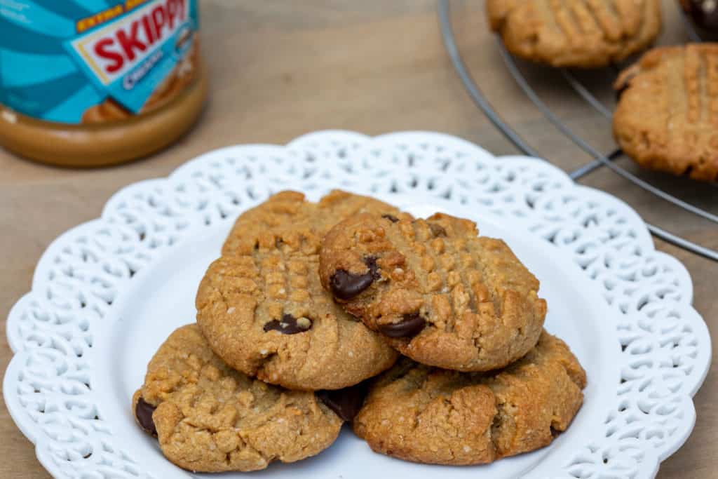 plate of almond flour peanut butter cookies with chocolate chips on plate with peanut butter and more cookies in background