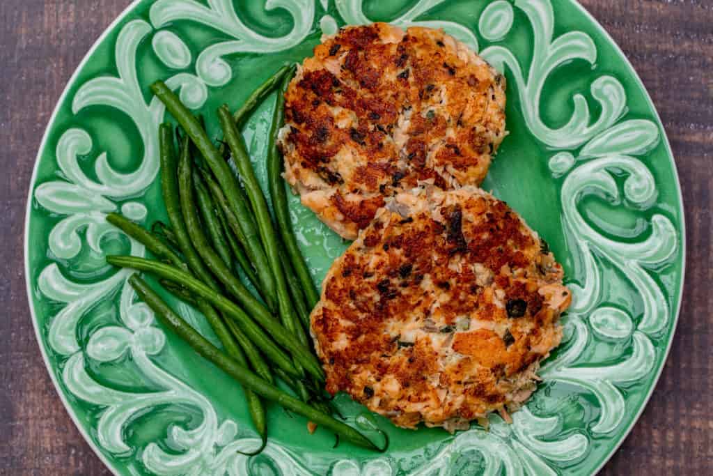 salmon cakes with green beans on green plate