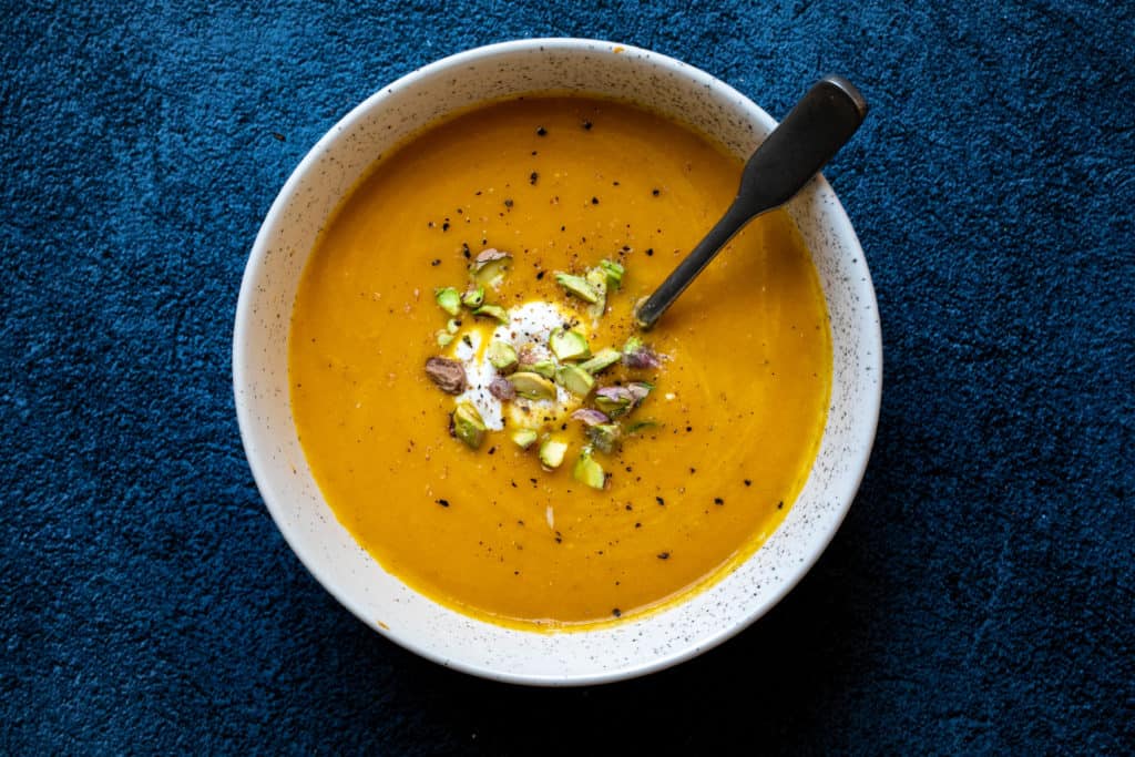bowl of carrot ginger soup with creme fraiche and pistachios