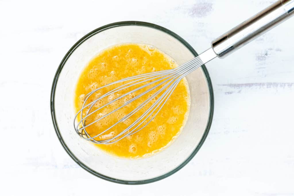 small bowl with egg, vegetable oil, and vanilla extract mixture with whisk