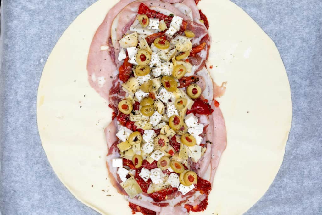 puff pastry dough lined with meats, cheeses, artichoke hearts, roasted peppers, and olives