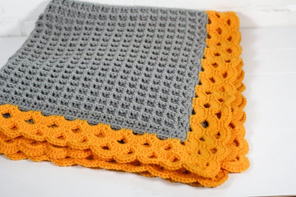 Stunning crochet blanket with a beautiful arcade stitch border. Free crochet pattern with 7 blanket sizes and video tutorials.