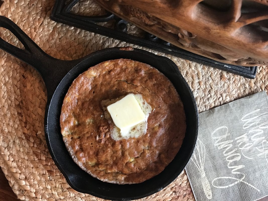 Banana bread made in a cast iron skillet topped with a slice of melting butter