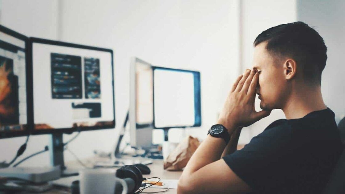 Man frustrated with Telstra service not working properly and looking at computers while stressed by problems. slow internet