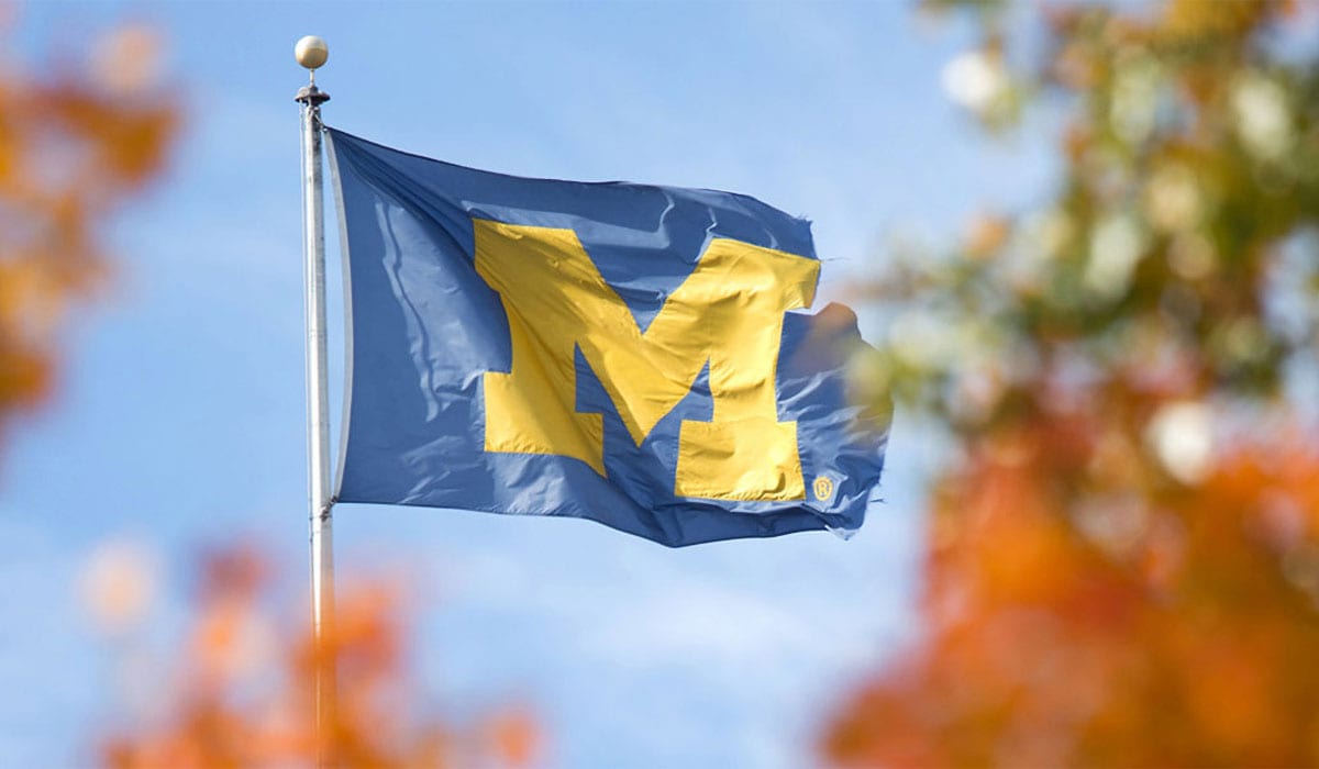 University of Michigan flag framed by orange and green leaves
