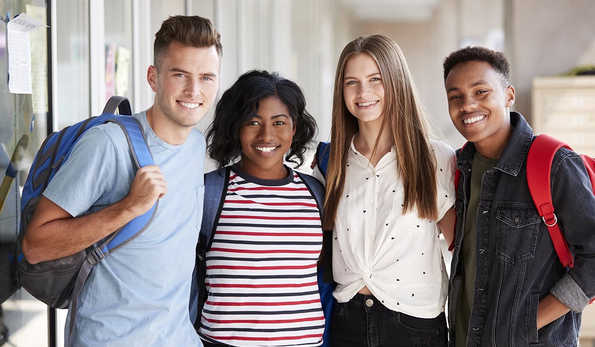 Portrait Of Smiling Male And Female College Student Friends In Corridor Of Building