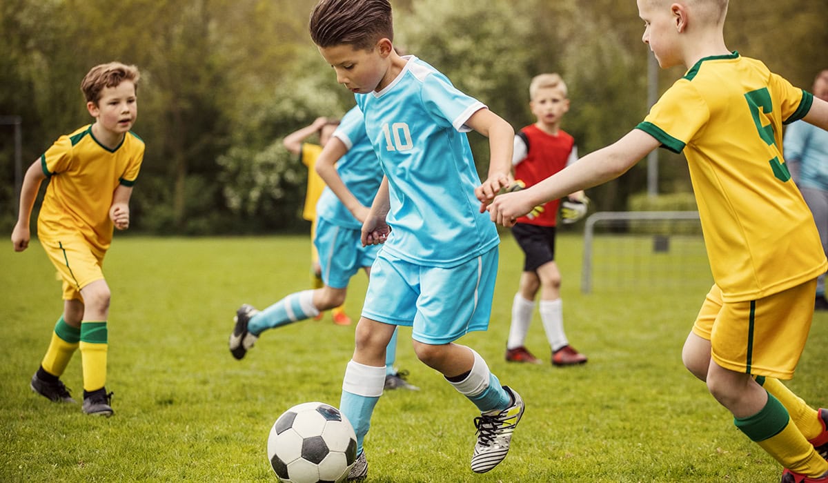Two Boys Soccer Teams Competing For The Ball During A Football Match