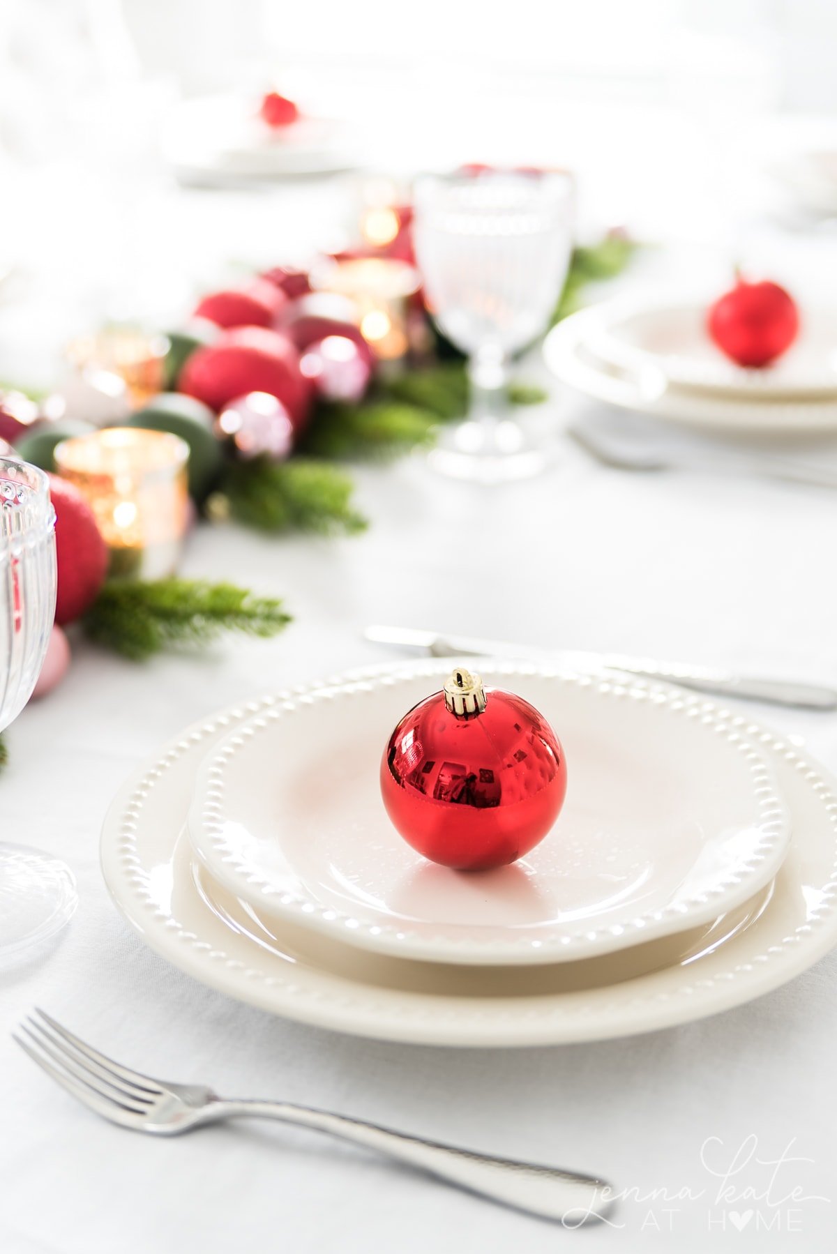 Festive Christmas table centerpiece using tree ornaments, votives and greenery