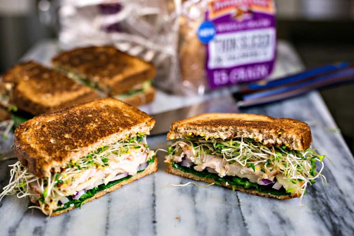 turkey melt sandwiches with alfalfa sprouts cut in half