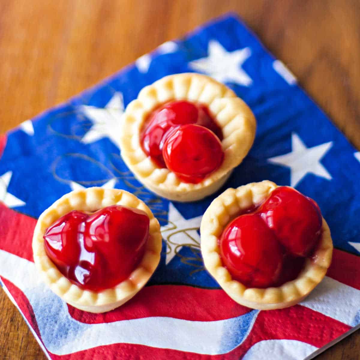 3 bite size cherry tarts on a patriotic napkin