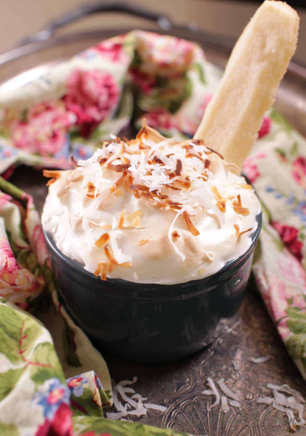 a single serving coconut cream pie without a crust with a cookie inserted in the middle of the pie.