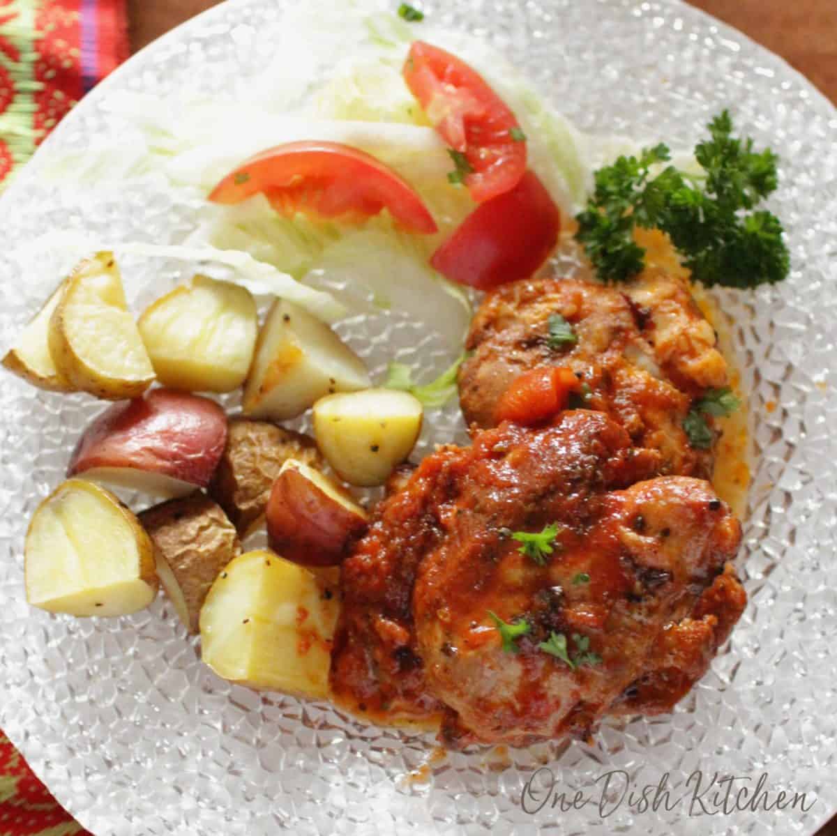 an overhead view of italian chicken with a salad and roasted potatoes on a plate | one dish kitchen