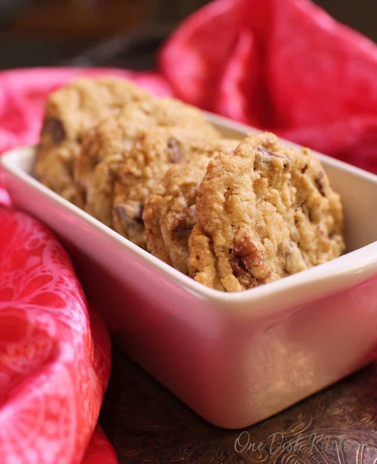Five cookies lined up in a row in a baking dish surrounded by a red silk cloth