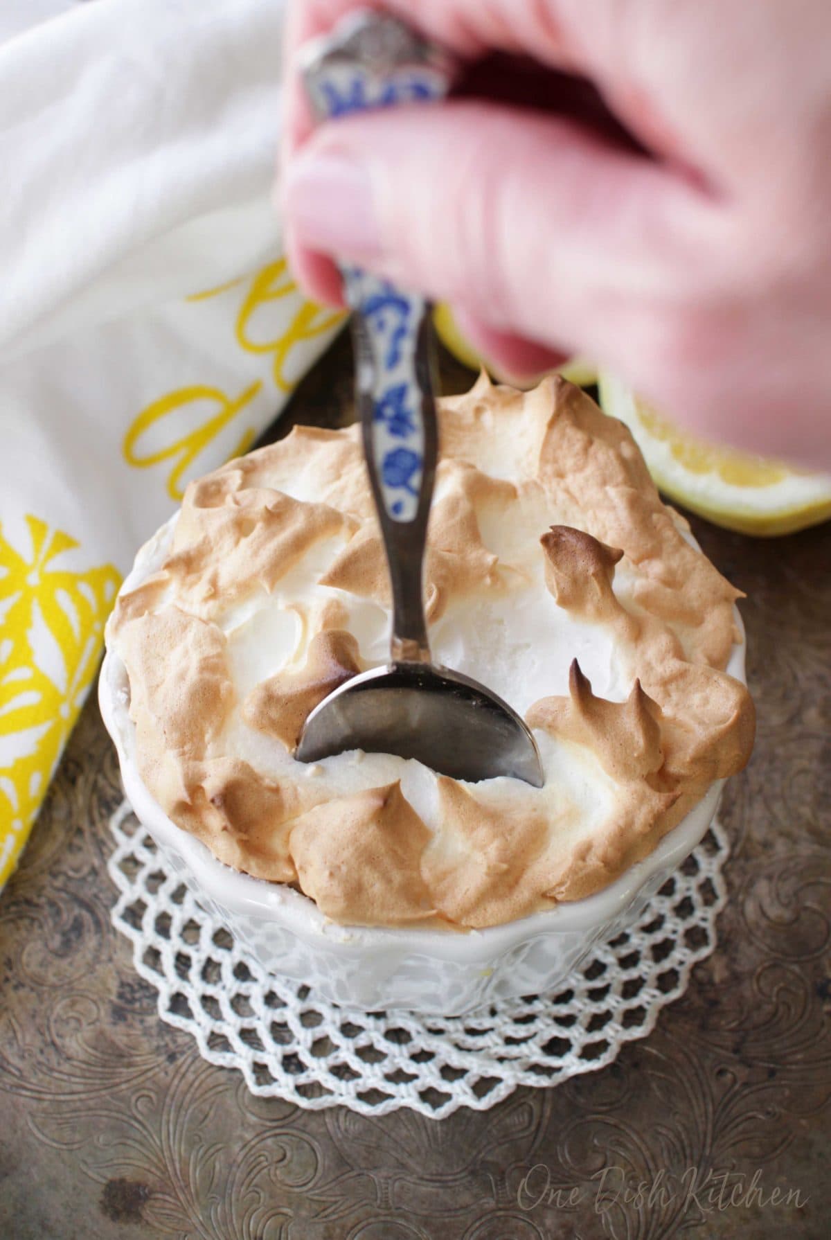 Sticking a spoon into a small lemon meringue pie and breaking through the meringue topping.