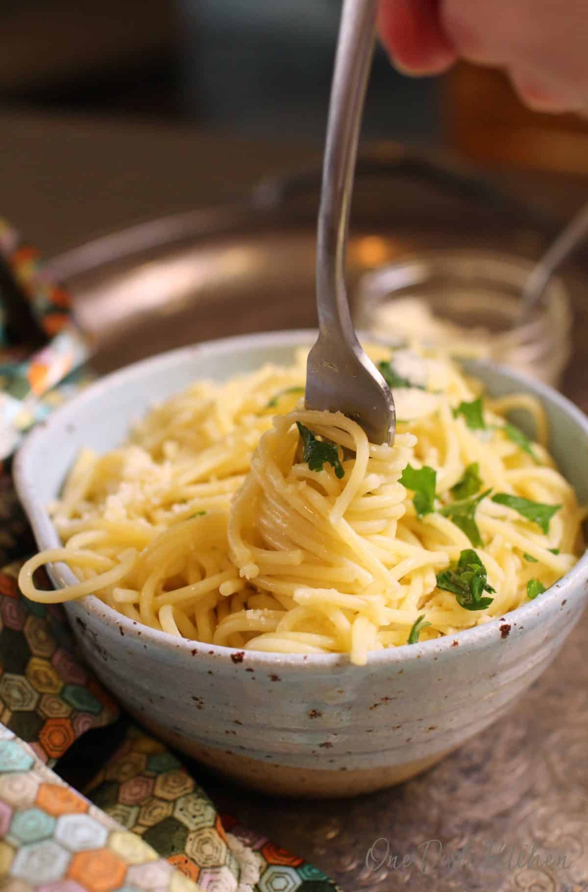 Strands of spaghetti wrapped around a fork in the center of a blue bowl on a tray.