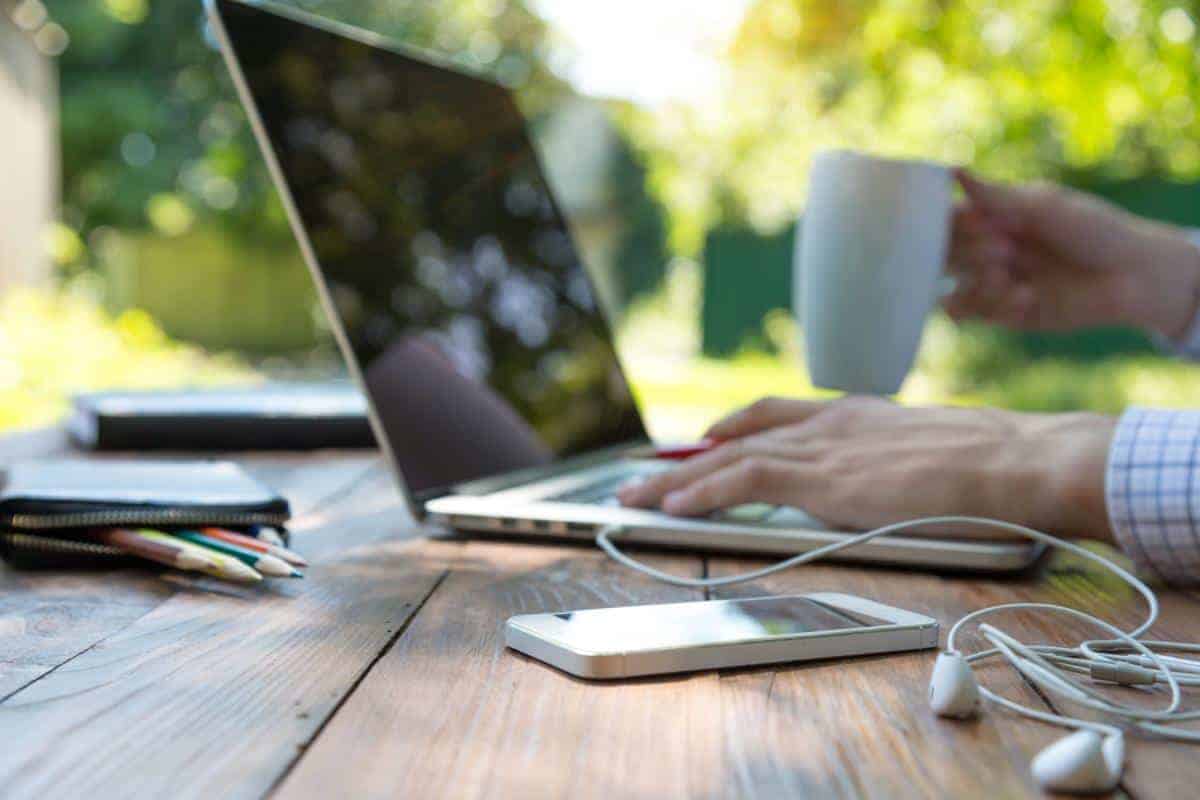 table top view of laptop with hands on keyboard and a white mug