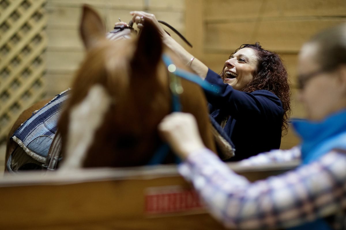 Nicole Walker, BU '01, owner and occupational therapist at Walker Therapy, saddles a horse before an equine therapy session. (AJ Reynolds/Brenau University)