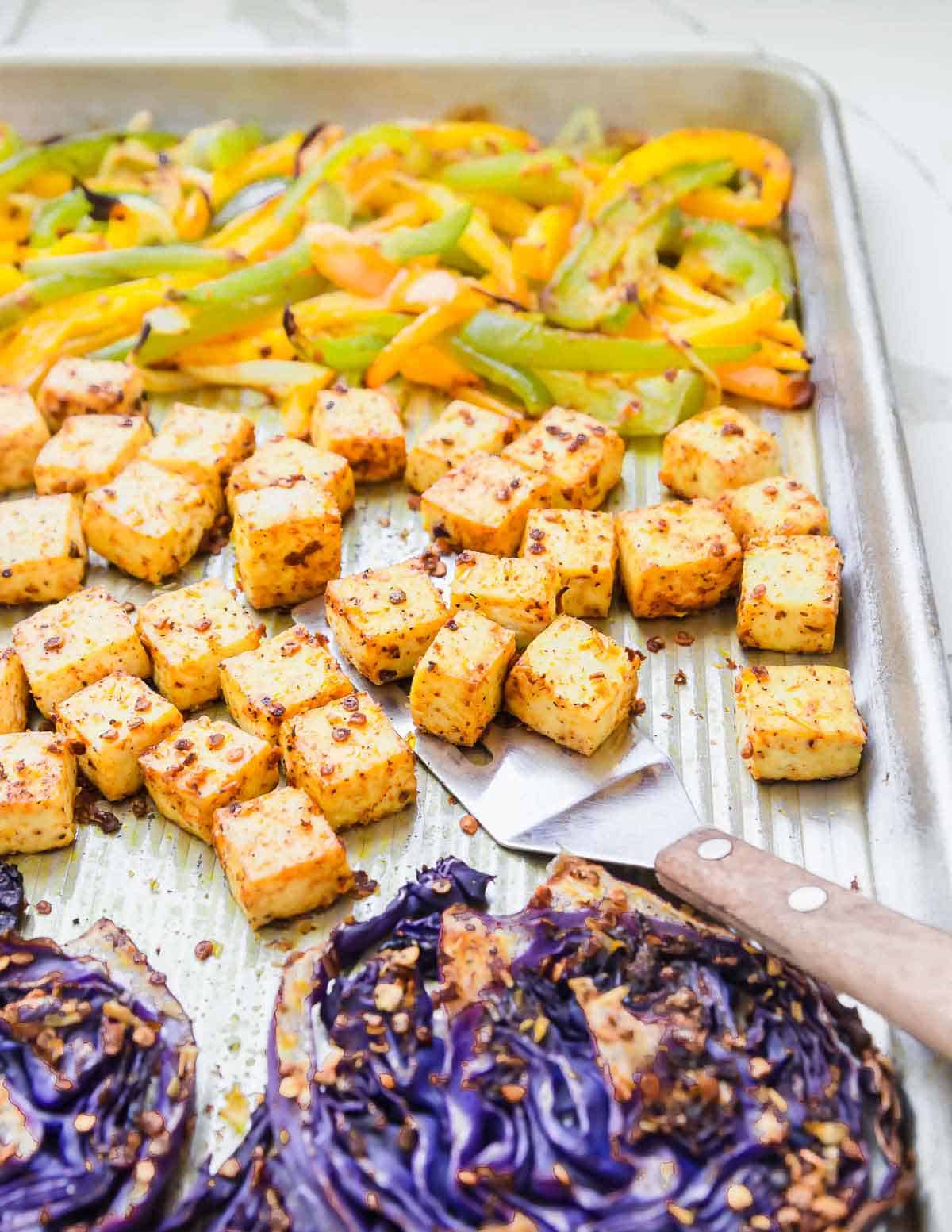 Roasted tofu, cabbage and peppers on a silver colored sheet pan. 