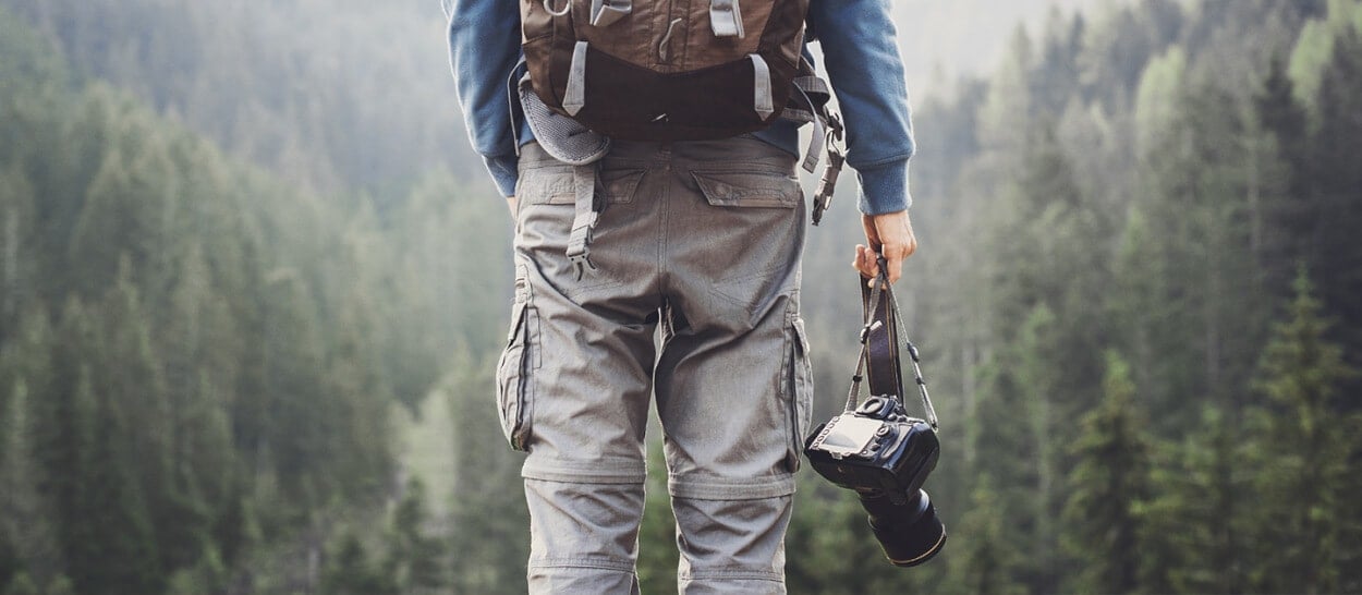 Adventurous travel photographer in forest for photographer insurance by Thimble