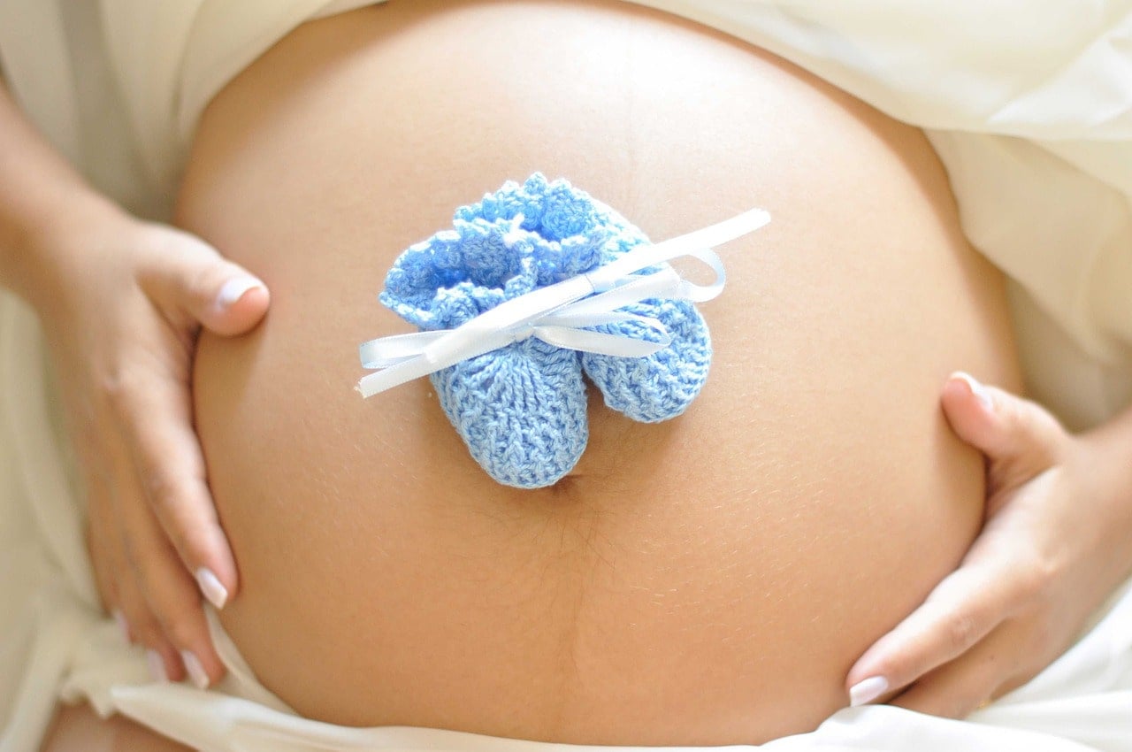 pancione di una donna incinta con scarpine azzurre