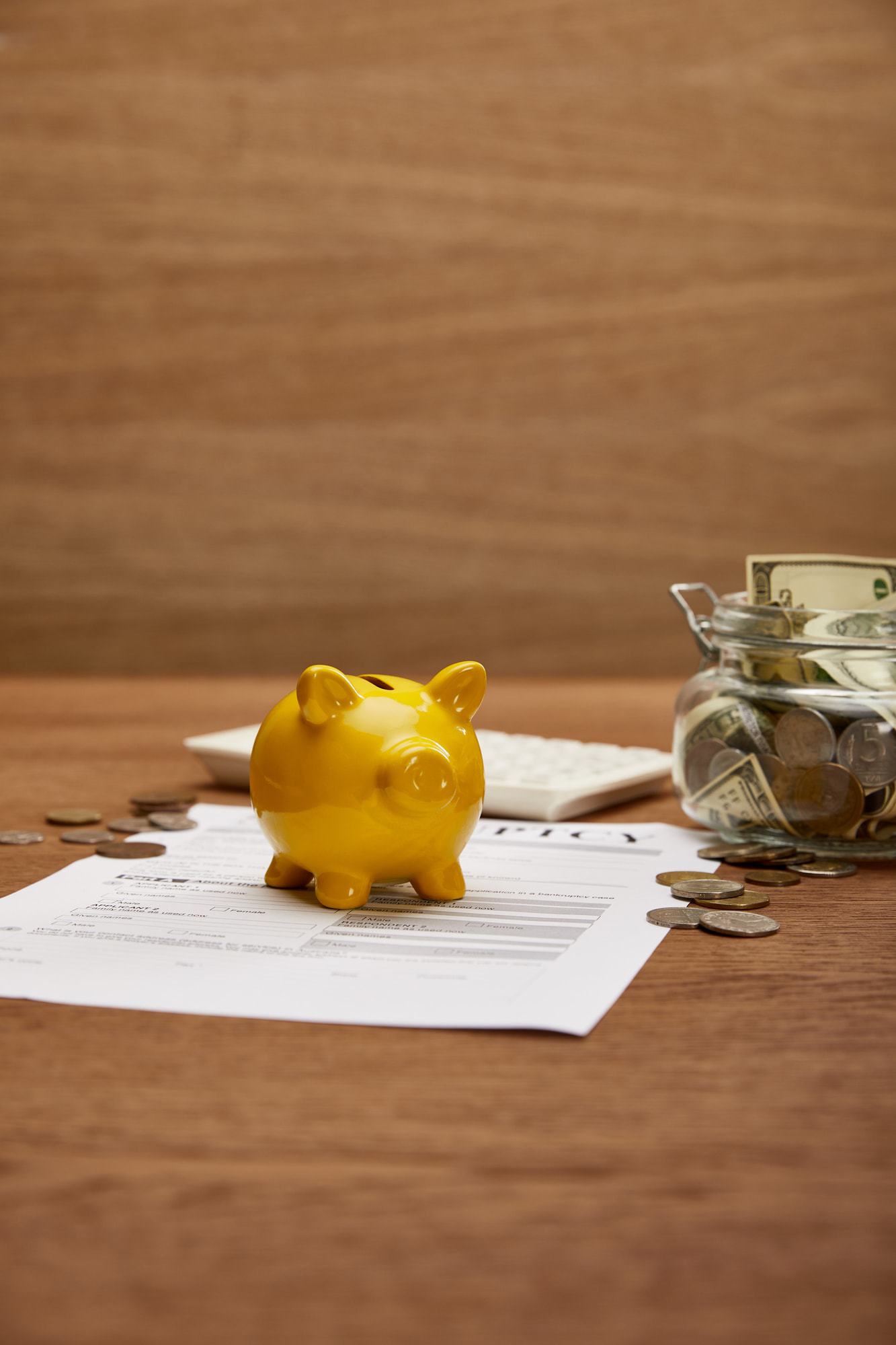 chapter 13 bankruptcy attorneys help you Yellow pigy bank sitting on bankruptcy paperwork with a jar of dollar bills