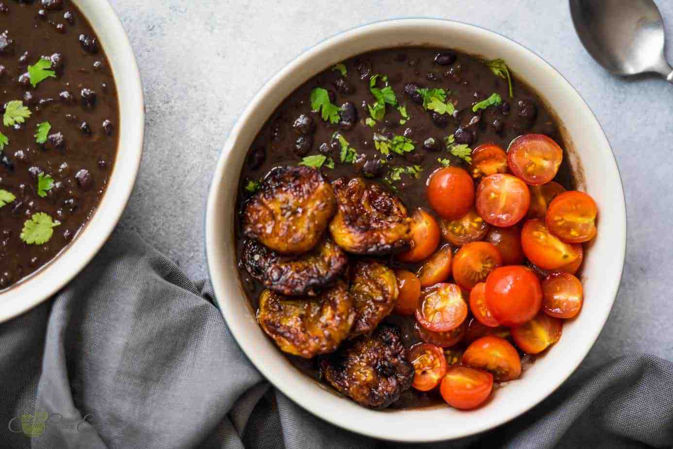 Two servings of instant pot cuban black beans with air fried plantains, tomatoes and sprinkle with fresh cilantro.