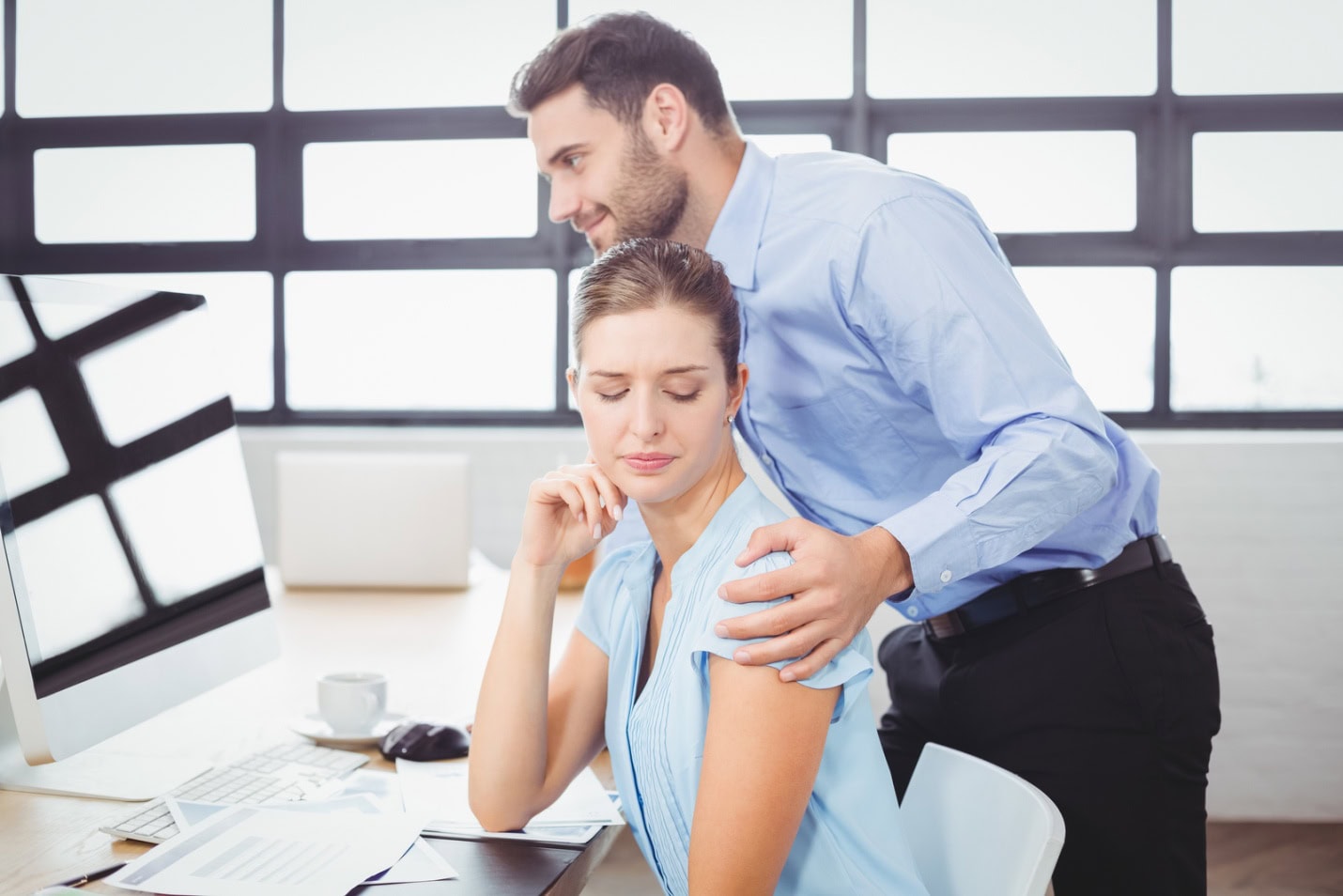 A male supervisor harasses a female employee by touching her inappropriately.
