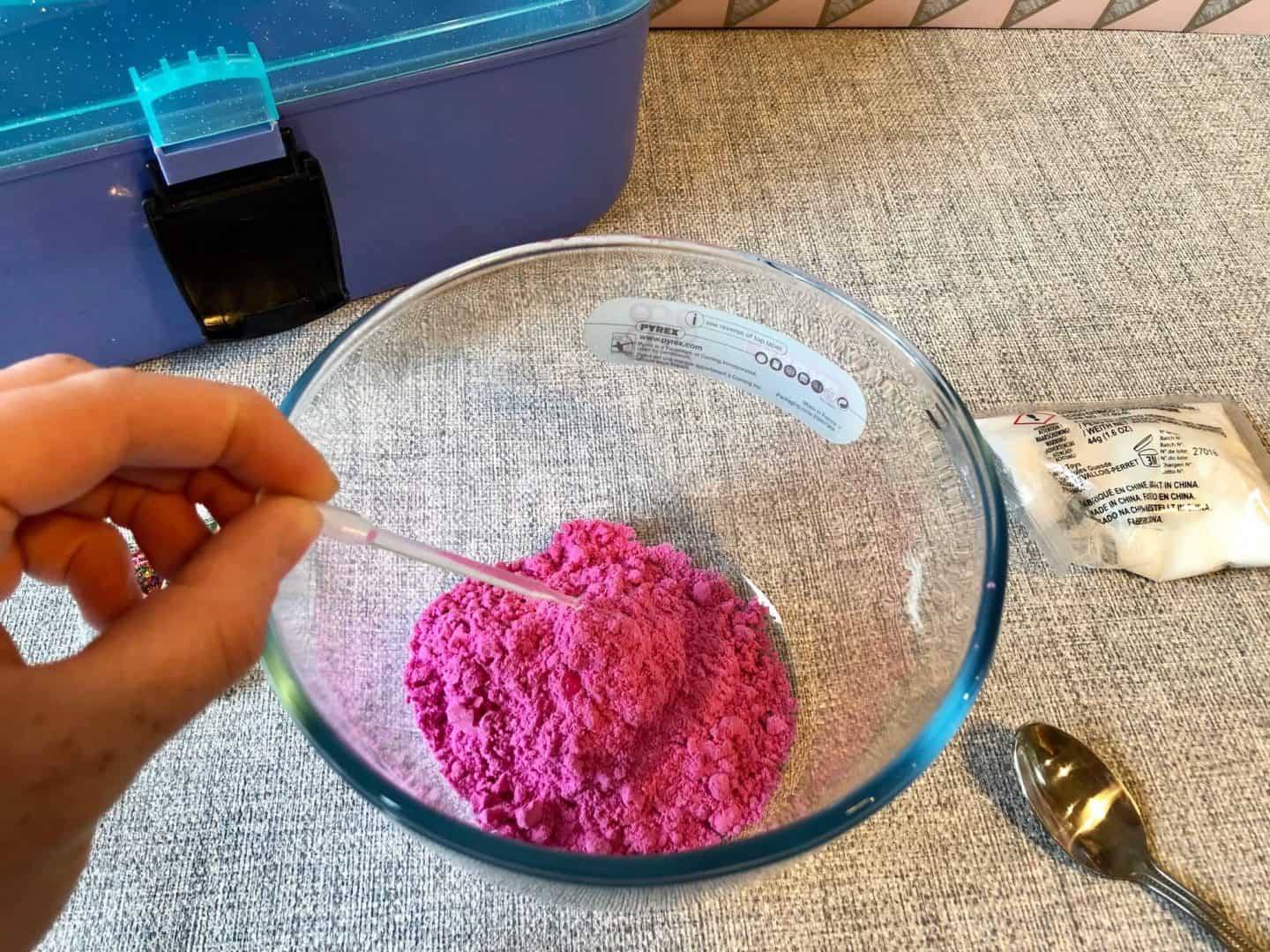 Adding the pipette of water to the coloured powder