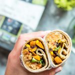 Hand holding two vegan burrito halves