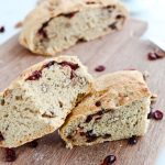 Cranberry pecan crusty bread cut into wedges on a wooden board