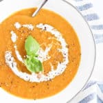 red lentil soup in a white bowl with cream and basil