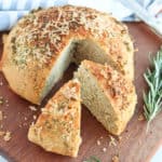 Crusty bread on a cutting board with cheese on top