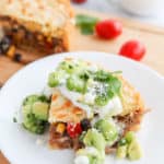 Slice of tamale pie with sour cream and green salsa over top