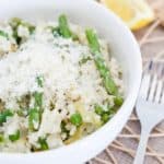 Instant Pot Lemon Risotto with Asparagus and Peas in a white bowl with a fork and lemon slices