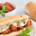 meatball sandwich on a white plate with basil