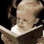 baby with glasses reading a book