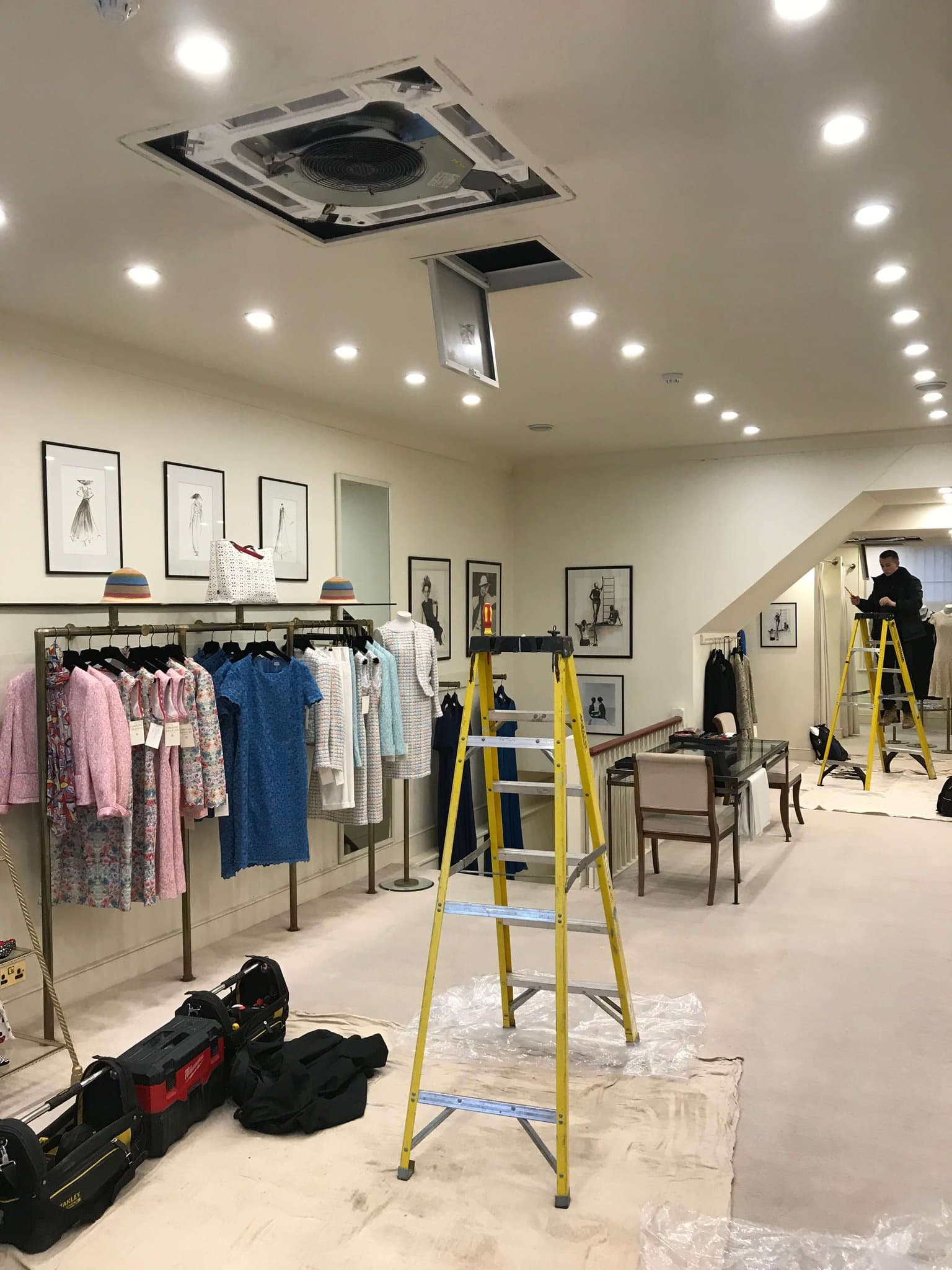 A ceiling air conditioning unit being installed in a fashion retail store
